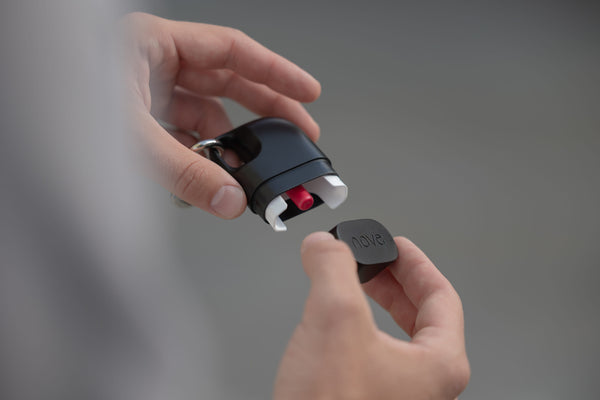 Hand opening Nove case with red nasal spray cartridge visible